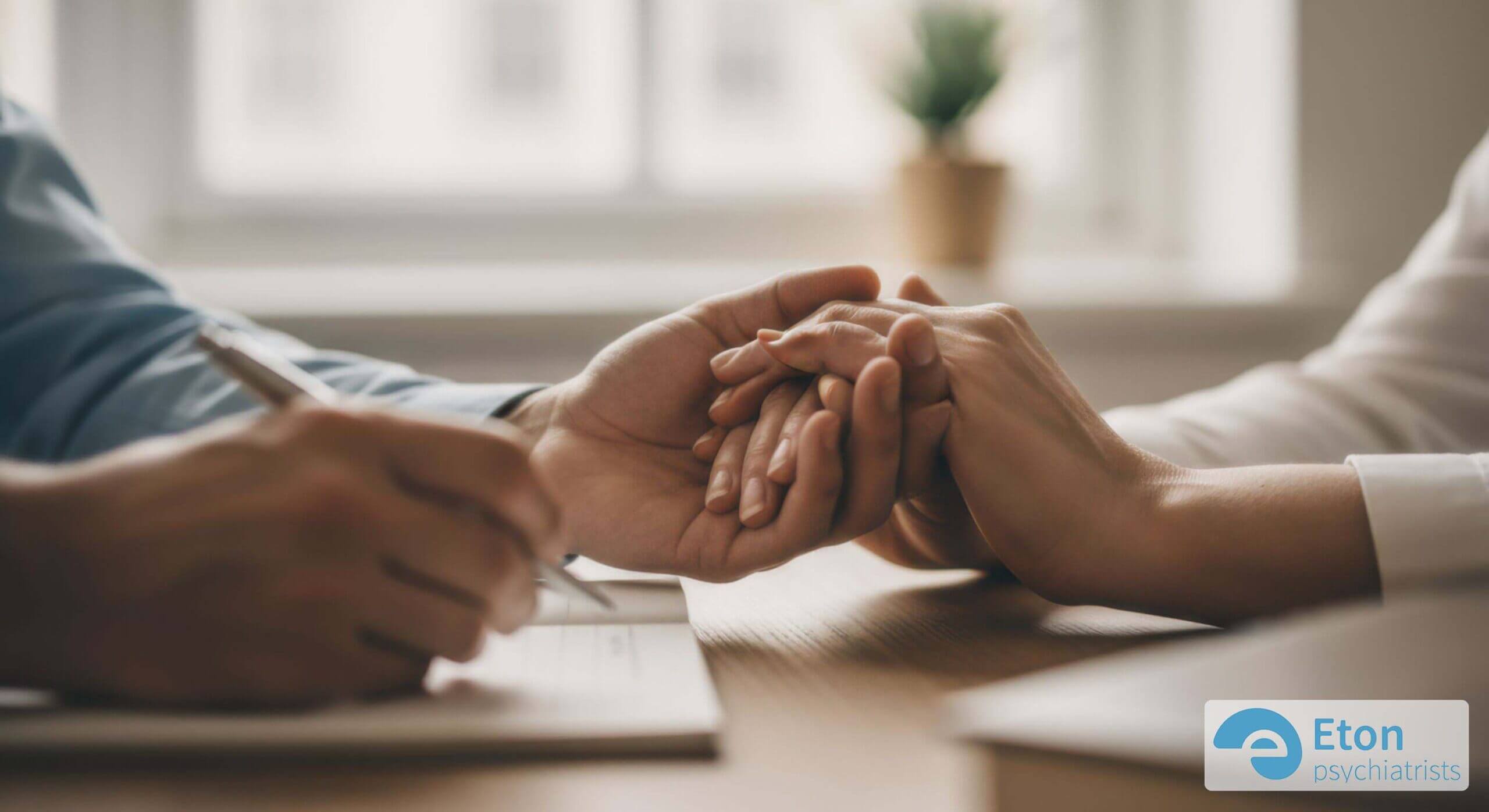 Two pairs of hands clasped supportively during a therapy session, symbolizing the positive impact of ADHD treatment.