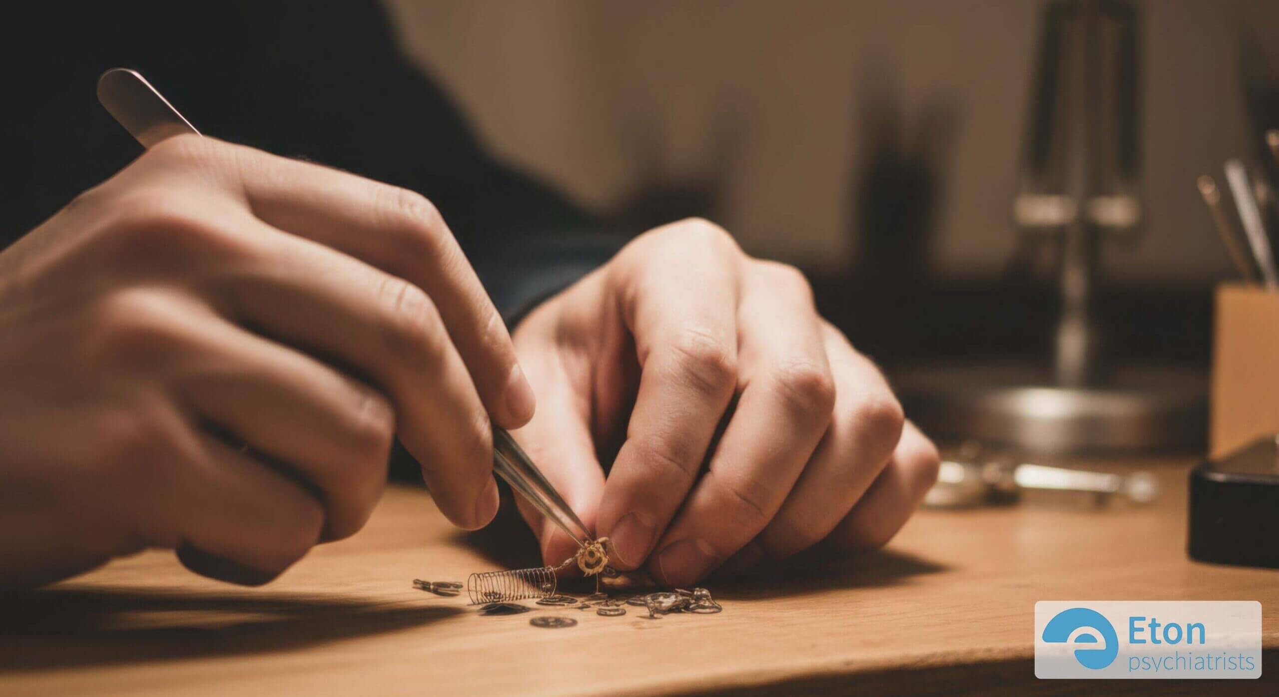 Hands meticulously arranging tiny, intricate components, highlighting autistic attention to detail.