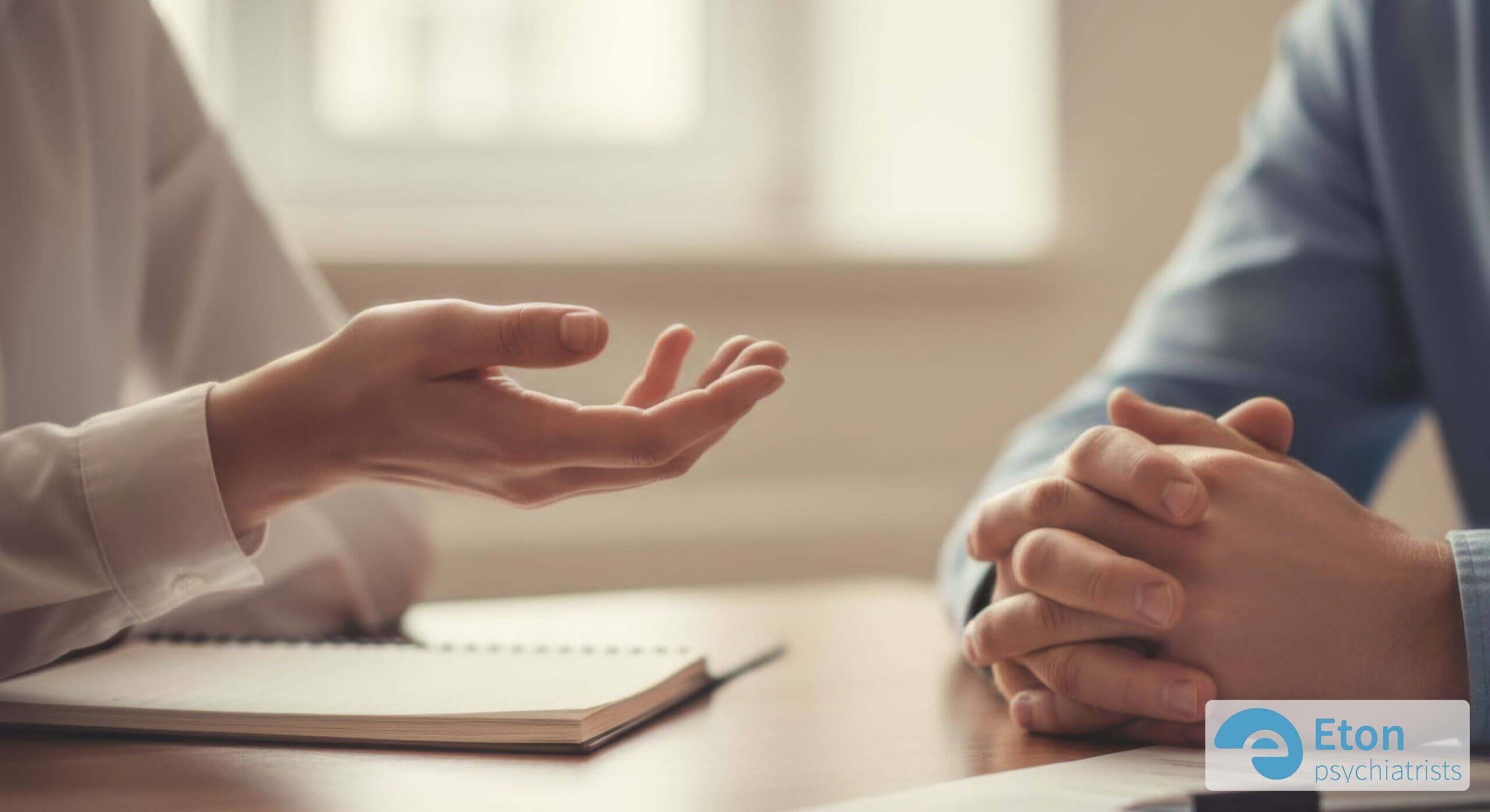 Close-up of a clinician's and patient's hands during a supportive consultation, symbolizing the autism assessment process.