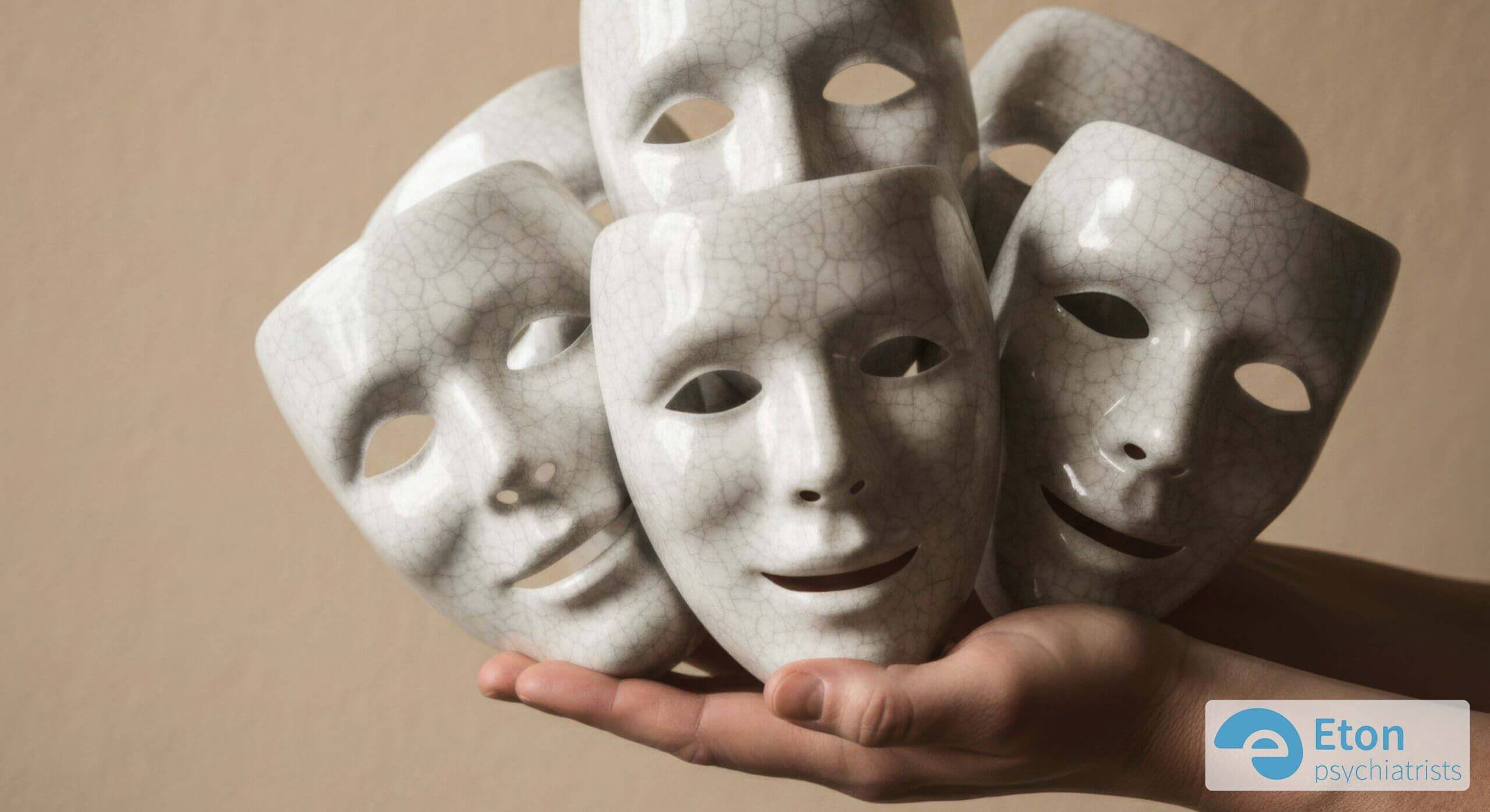 Hands holding multiple theatrical masks, representing the exhausting effort of autistic masking in adults.